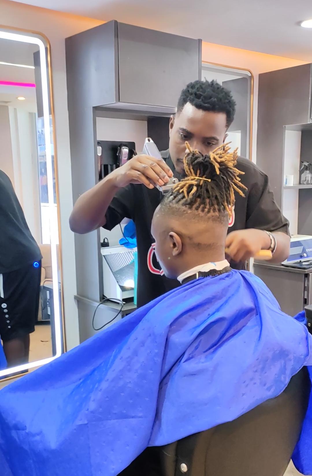 Barber working on dreadlocks at Maimo Mancave